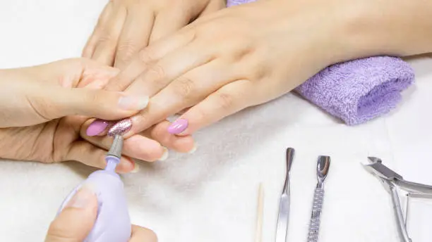 Manicure. Hardware manicure. Removal of old gel varnish in the salon. Manicure master doing beauty procedure for client. Manicurist is applying electric nail file drill to manicure on female fingers
