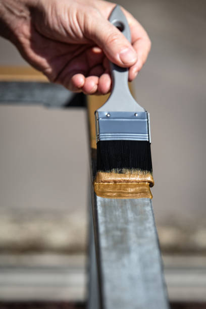 a man is painting a metal railing with copper varnish, close up outdoor shot a man is painting a metal railing with copper varnish, close up outdoor shot brush fence stock pictures, royalty-free photos & images