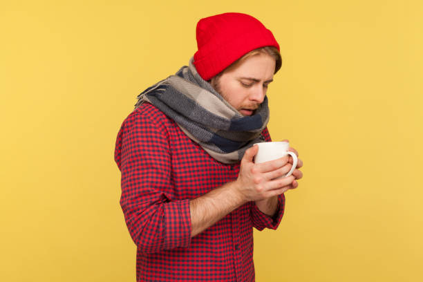 istock Flu-sick guy treated with warm tea, holding cup feeling unwell with sore throat, high temperature fever, seasonal influenza 1253479095