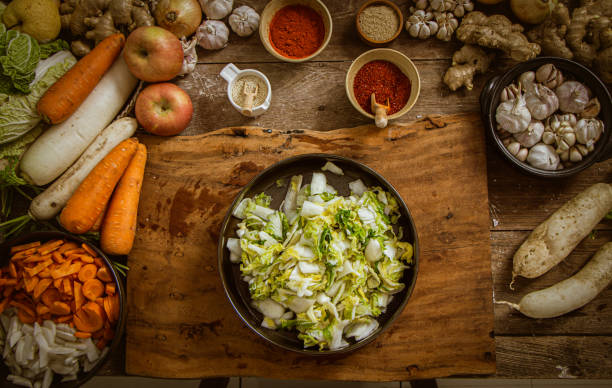 top view Hand holding knife and slice kimchi cabbage on wooden cutting board for cooking, Korean food