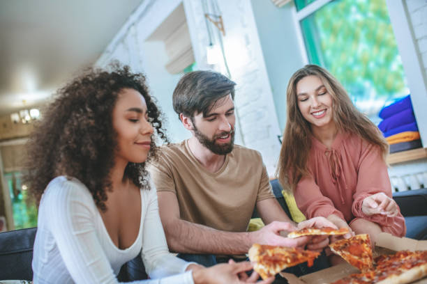 istock Guy and two girls taking pizza from box. 1253484406