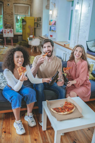 istock Eating and drinking guy and two girls at home. 1253484413