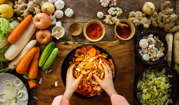 top view Hand holding knife and slice kimchi cabbage on wooden cutting board for cooking, Korean food