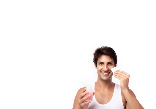 Young caucasian man hold toner bottle, using cotton pad and cleaning his face, apply it to beauty face for firming pores, help skin smooth bright, lively after shower. Isolated on white, copy space joven hombre caucásico mantener botella de tóner, el uso de almohadilla de algodón y la limpieza de su cara, aplicarlo a la cara de belleza para reafirmar los poros, ayudar a la piel lisa brillante, vivaz después de la ducha. aislado en blanco, espacio