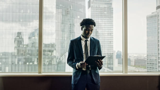 istock African ethnicity businessman reading documents. Office interior with a view 1253486224