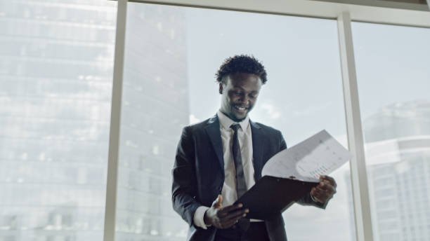 istock African ethnicity businessman reading documents. Office interior with a view 1253486514