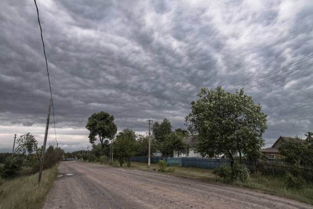 Beautiful, and epic thunderclouds in a village with a road to the unknown. The sky as the forerunner of a hurricane in Europe. Stock photo clouds for design stock photo