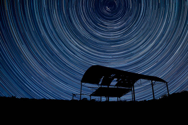 istock Digital composite image of star trails around Polaris with derelict barn silhouette 1253488889