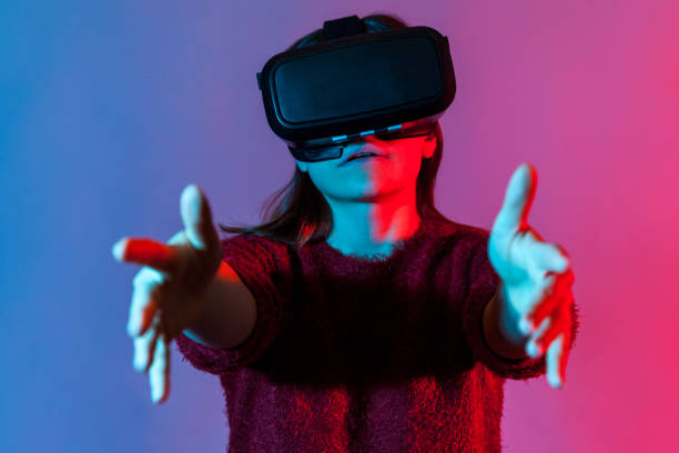 istock Closeup girl with virtual reality glasses on head playing game simulator, standing outstretched hands 1253489968
