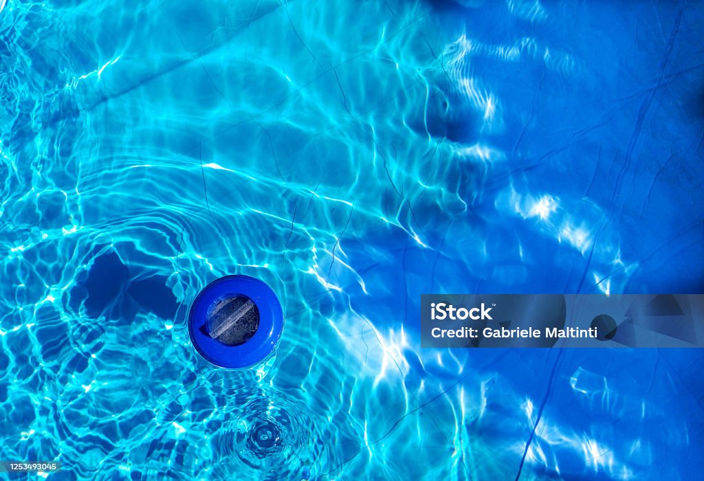 Floating plastic chlorine dispenser and blue water seen from above Floating plastic chlorine dispenser and blue water seen from above. Chlorine dispenser is used to disinfect the swimming pool Swimming Pool Stock Photo