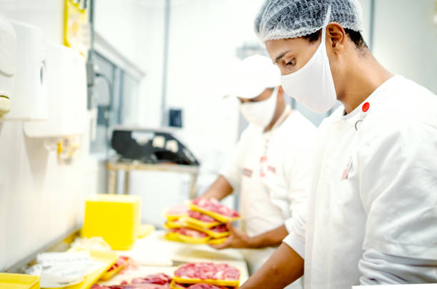 boucher travaillant dans une épicerie, coupant la viande - butcher butchers shop meat store photos et images de collection