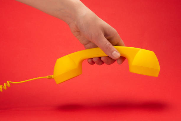 istock Yellow handset on a red background in woman hand. 1253493991