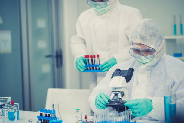 istock Group of Scientists with a microscope in laboratory, developing a vaccine. They Work in an Electronic Components Manufacturing Factory. 1253497597