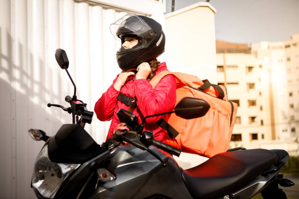 istock Delivery biker with crash helmet off - motogirl 1253498902