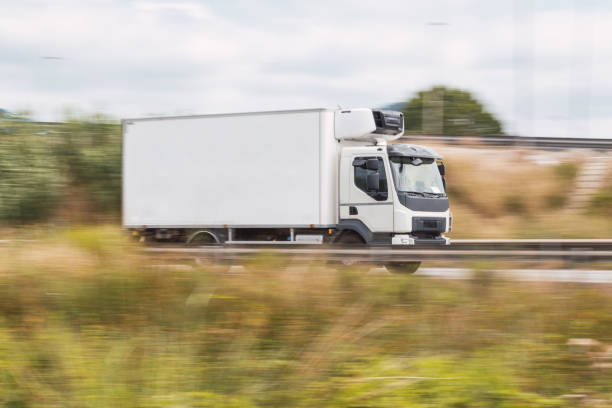 panning of a white truck with a trailer on a road, highway, movement effect - tow truck heavy truck delivering imagens e fotografias de stock