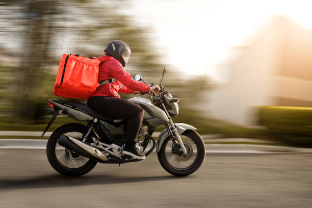 lieferbiker ankunft am ziel - motogirl - motorradfahrer stock-fotos und bilder