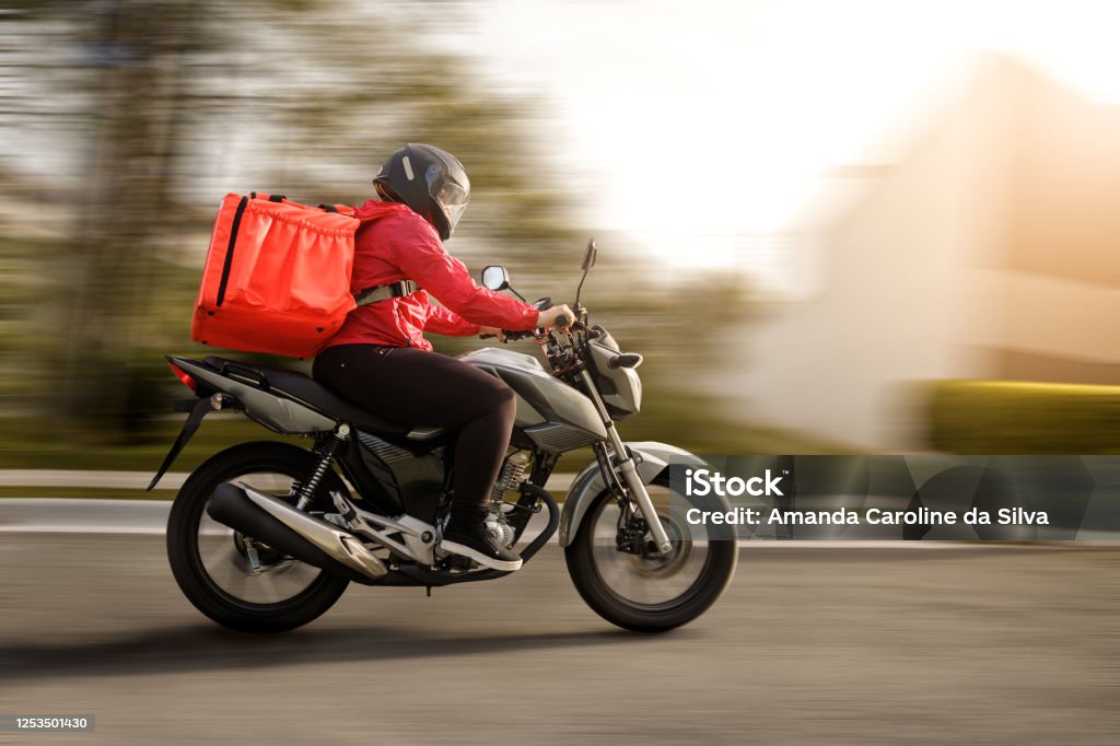 Delivery biker arriving at destination - motogirl Motorcycle Stock Photo