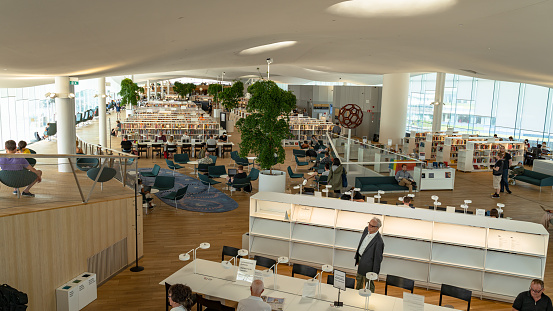 This pic shows New Helsinki central library Oodi. This shows Oodi interior. Light and spacious modern northern architecture. Bookshelves, working space. People reading, working, relaxing, studying.