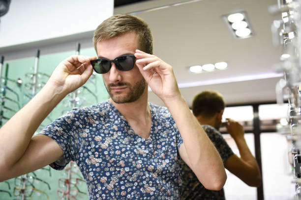 istock Young man chooses glasses in optic shop 1253505104