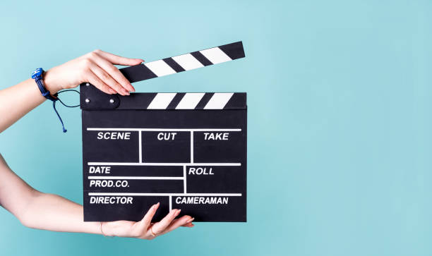 istock Female hands holding a clapper board isolated on blue 1253506217