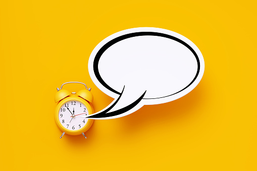 Yellow alarm clock and white speech bubble over yellow background. Horizontal composition with copy space.