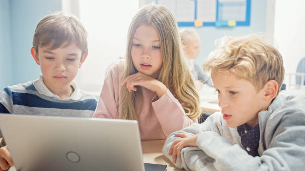 istock Elementary School Classroom: Diverse Group of Brilliant Children Using Laptop Computer for Software Programming, Talking and Working as a Team. Kids Learning Software Design and Creative Thinking 1253508015