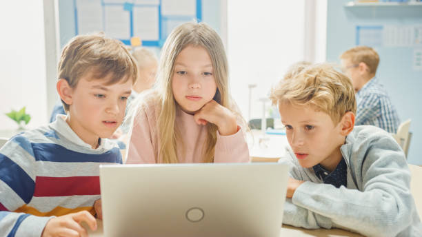 istock Elementary School Classroom: Diverse Group of Brilliant Children Using Laptop Computer for Software Programming, Talking and Working as a Team. Kids Learning Software Design and Creative Thinking 1253508047
