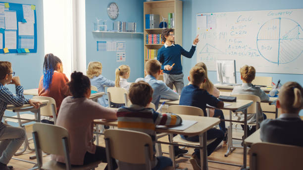 istock Caring Teacher Explains Lesson to a Classroom Full of Bright Diverse Children. In Elementary School with Group of Smart Multiethnic Learning Science, Listening to a Teacher with Great Interest 1253508072