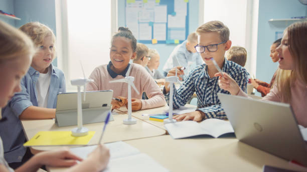 istock In the Elementary School: Class of Smart Young Children Work as a Team Using Tablet Computers to Program Wind Turbines. Classroom with Kids Learning about Eco-Friendly Forms of Renewable Energy 1253508715