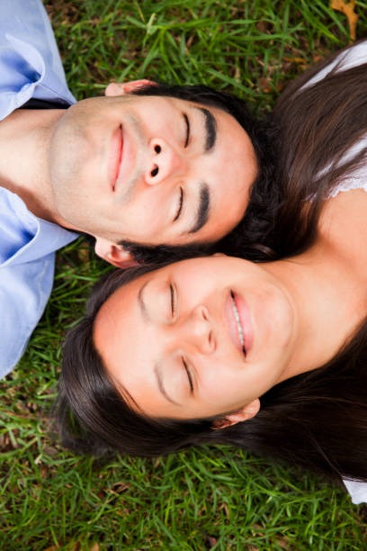istock Happy couple lying down on grass with eyes closed 1253508937