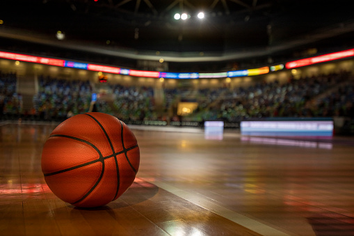 Basketball on court in stadium.