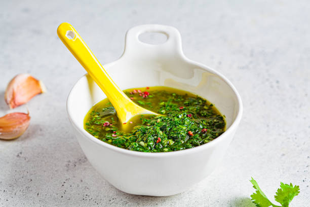 Fresh traditional chimichurri sauce for barbecue meat in a white bowl, light background. Fresh traditional chimichurri sauce for barbecue meat in a white bowl, light background. chimichurri stock pictures, royalty-free photos & images