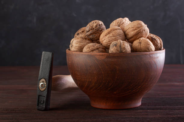 istock Walnut in pottery and hammer on a wooden table 1253515611
