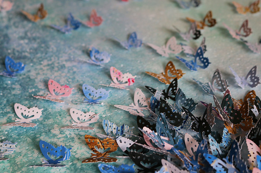 Stock photo showing homemade crafting art work with card and paper butterflies embossed and glued on abstract watercolour painting that has been painted on a stretched canvas. The butterflies were cut out using a butterfly design hole punch.
