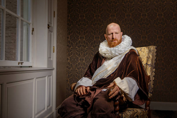 Redhead traditional dutch man reading a book by candlelight Handsome redhead traditional dutch man wearing historically correct outfit reading a book by candlelight in a typical townhouse drawing room renaissance stock pictures, royalty-free photos & images