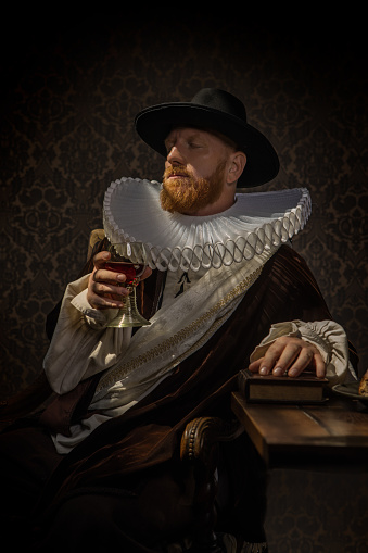Portrait of a handsome redhead traditional dutch nobleman wearing historically correct outfit in a typical townhouse drawing room
