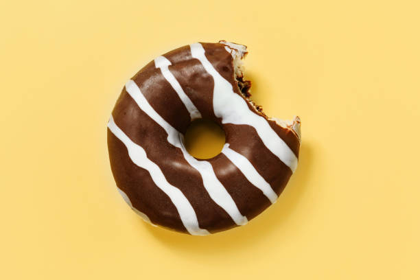 istock A bitten chocolate donut on a yellow background 1253518323