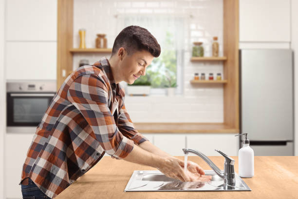 istock Young man washing hands in a kitchen 1253522393