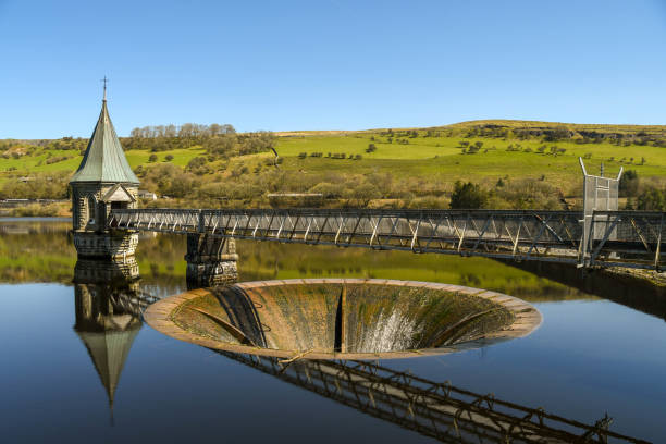 Bell mouth slipway and valve tower on a reservior Merthyr Tydfil, Wales - April 2018: The bell-mouth spillway and valve tower on the Ponsticill reservoir. The reservoir is operated by Welsh Water, a not-for-profit company merthyr tydfil stock pictures, royalty-free photos & images
