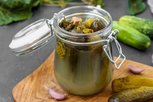 istock Pickles - canned fermented cucumbers in glass jar on dark background, horizontal orientation 1253524767