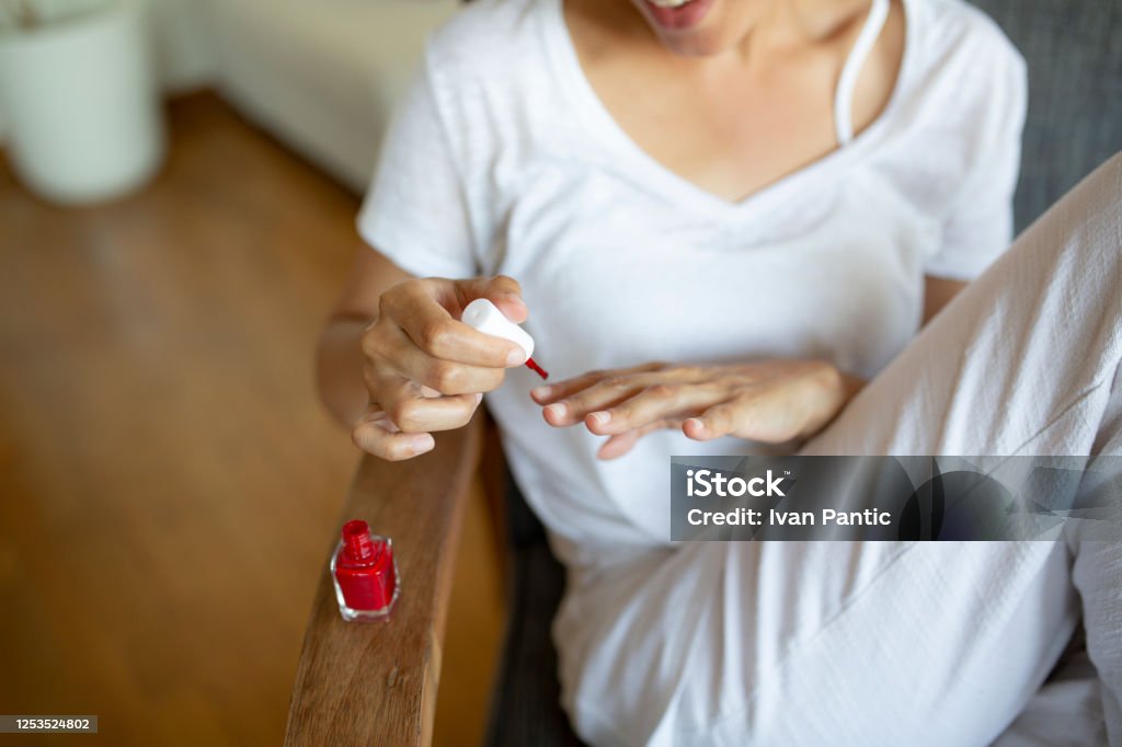 Focus on a young African American woman at home, giving herself a beauty treatment Focus on an African American woman painting her fingernails, having herself a manicure at home Nail Polish Stock Photo
