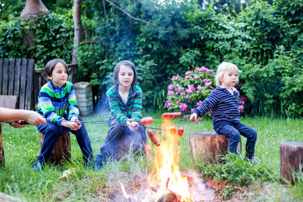 istock Happy kids roasting sausages on campfire 1253524957