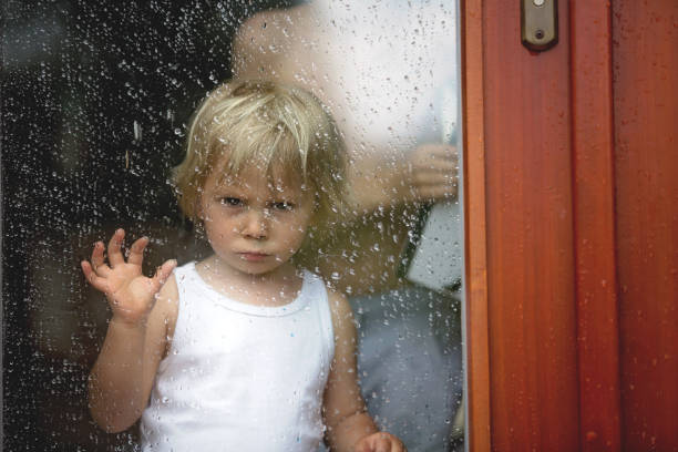 istock Sad child behind the window on rainy day 1253525134