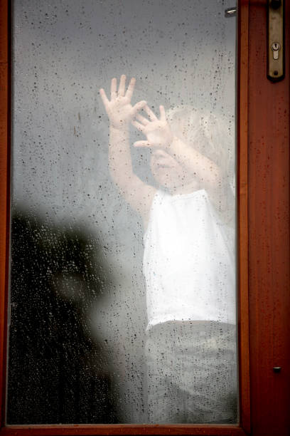 istock Sad child behind the window on rainy day 1253525271
