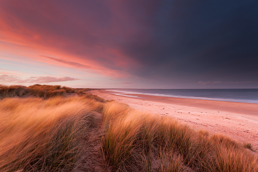 Stormy sunset over sand dunes and the beach and sea
