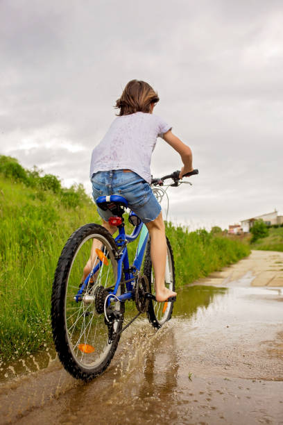 istock Child, boy, riding bike in muddy puddle, summer time 1253529108
