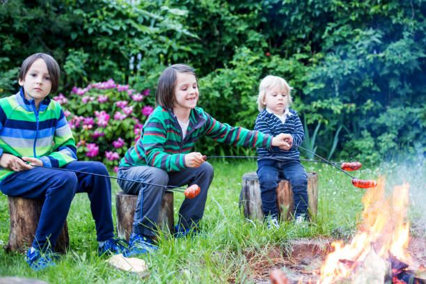 istock Happy kids roasting sausages on campfire 1253529137