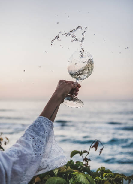 Woman flowing white wine from winelgass over beautiful sunset