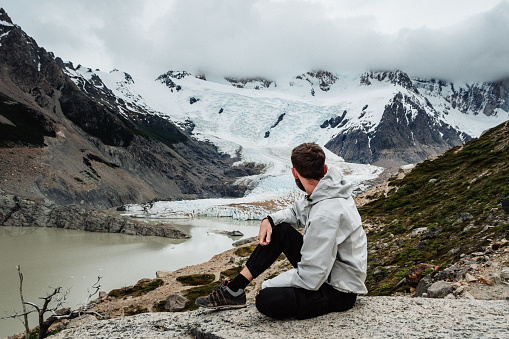 Man sitting and enjoying the view of  Glacier Torre in Patagonia, Argentina