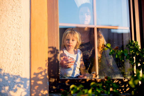 istock Child, toddler boy, looking through window 1253533628